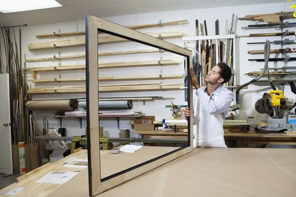 man looking at large frame on table