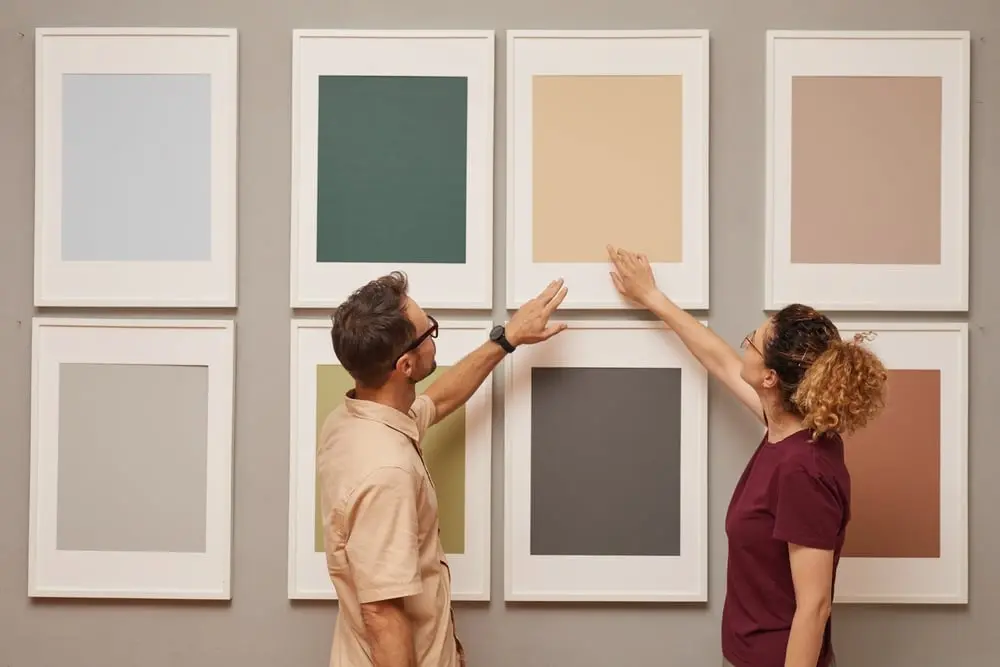 man and woman looking at various frames on a wall