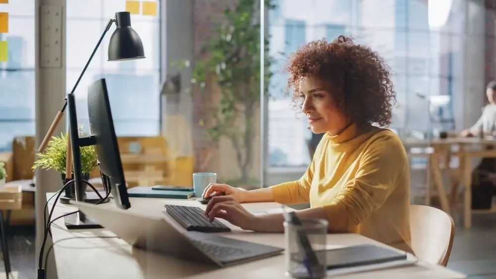 Woman in yellow sweater working on computer in store