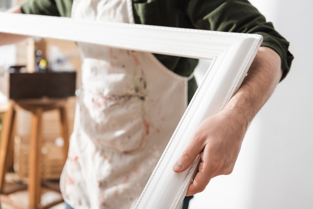 man holding white hand crafted picture frame