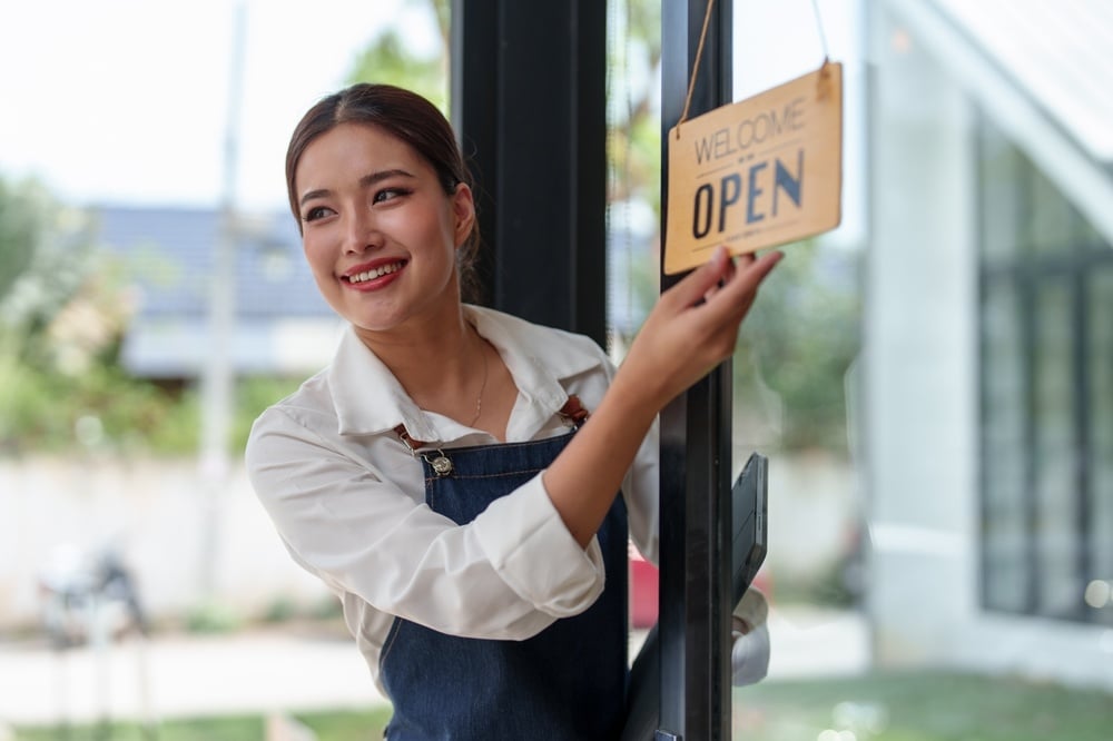 woman turning open sign in front of business